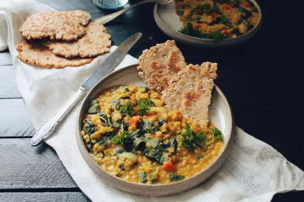 Un plat réconfortant de lentille corail recette, garni de persil frais et servi avec des galettes croustillantes.