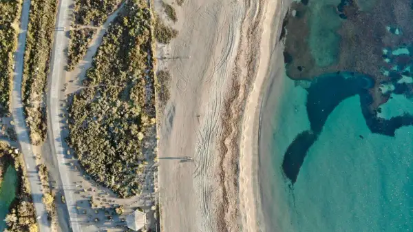 Vista aérea de las playas de Roquetas de Mar con arena fina, vegetación árida y aguas cristalinas.