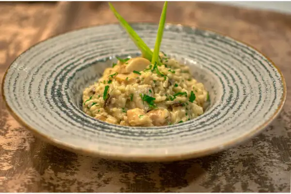 Un crémeux risotto champignon, parsemé de persil frais et garni d'une touche verte. Un délice pour les yeux et les papilles.