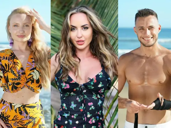 Trójka uczestników Hotel Paradise 2: blondynka w pomarańczowym stroju, brunetka w kwiecistej sukience i mężczyzna z opaską na ręce na tle plaży.