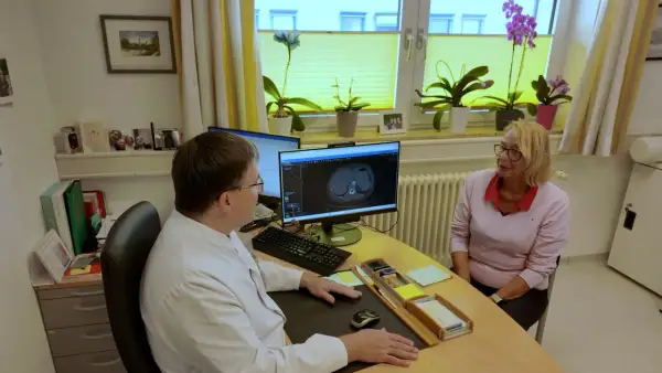 Arzt bespricht CT-Scan mit Patientin. Die Lebenserwartung bei Lungenkrebs Stadium 2 ist ein wichtiges Thema.