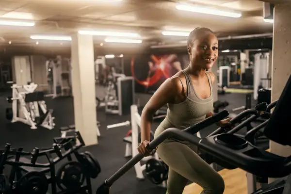 Femme souriante sur un tapis roulant, un excellent exercice pour perdre du ventre rapidement.