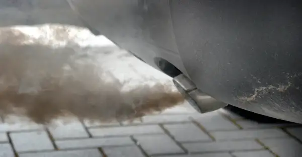 Gęsty dym wydobywa się z rury wydechowej samochodu, co może sugerować problem z DPF. Jak wypalić DPF na postoju, gdy auto kopci?