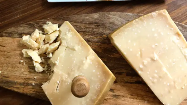Due pezzi di formaggio stagionato, uno con scaglie e un piccolo tappo di legno, mostrano la differenza tra Gran Biraghi e Grana Padano.