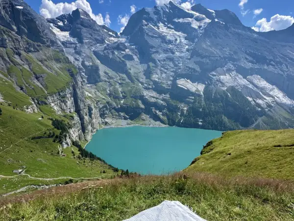 Türkisblaue Oeschinensee Schweiz, umrahmt von steilen, grünen Berghängen und schneebedeckten Gipfeln. Ein idyllischer Ort für Wanderer.