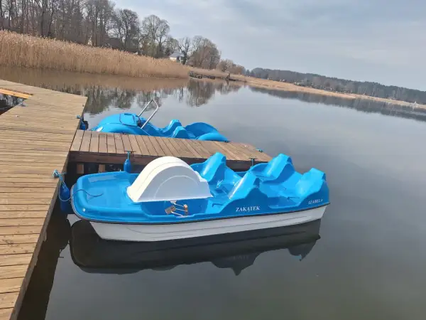 Błękitne rowerki wodne czekają na gości przy drewnianym pomoście. To idealne miejsce na wypoczynek, jak w słynnym polu namiotowym Sława.