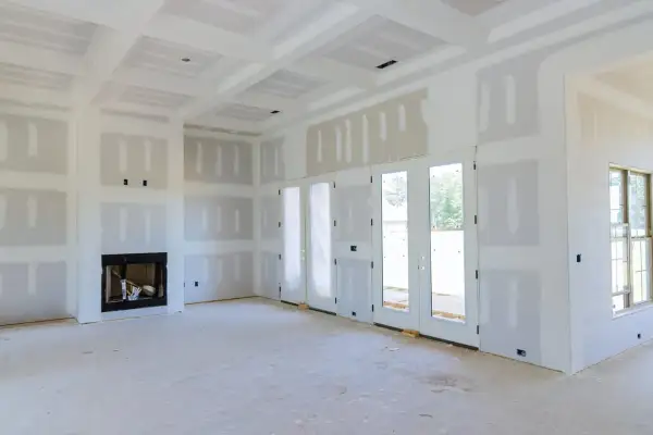 Interni di una casa in costruzione, con pareti e soffitto in cartongesso pronti per essere stuccati. Si intravede un camino.