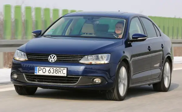 Ciemnoniebieski VW Jetta MK6 jedzie po autostradzie. Kierowca patrzy przed siebie.