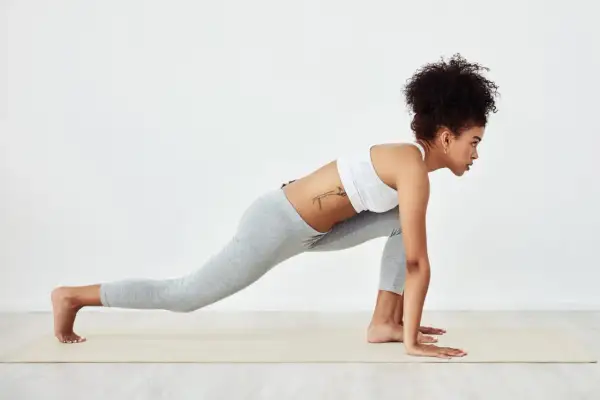 Woman in athletic wear performs a low lunge, stretching her upper body after a workout.