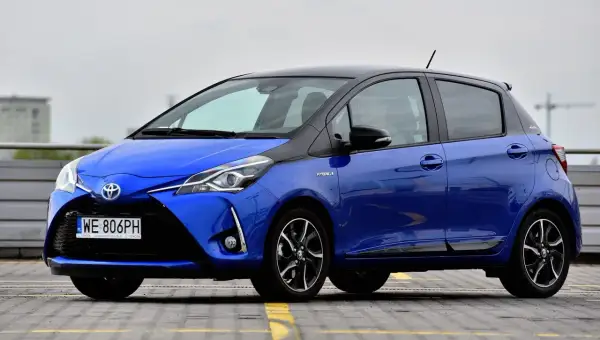 Niebieska Toyota Yaris Hybrid z czarnym dachem, zaparkowana na zewnątrz.