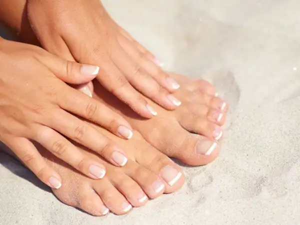 Letnie stopy z klasycznym pedicure hybrydowym na plaży.