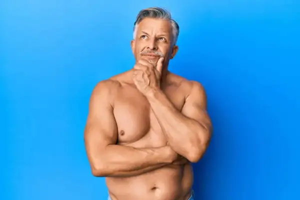 Ein nachdenklicher Mann mit grauen Haaren und Bart, dessen Oberkörper trainiert ist, was auf gut entwickelte Typ 1 Muskelfasern hindeutet.