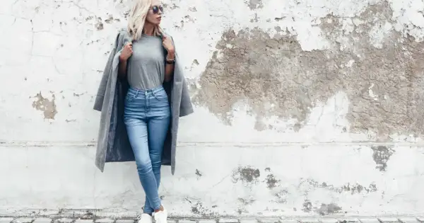 Modelka w jasnych jeansach skinny i szarym płaszczu. Dowiedz się, jakie jeansy do jakiej figury pasują najlepiej.