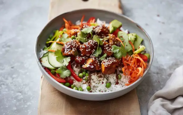 Pyszny bowl z kurczakiem w sosie teriyaki, ryżem, chrupiącą marchewką, ogórkiem, groszkiem i papryką.