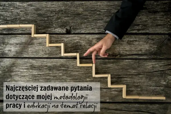 Palce wskazujące mężczyzny w garniturze schodzą po drewnianych schodkach, symbolizując podróż wgłąb siebie i analizę metod pracy.