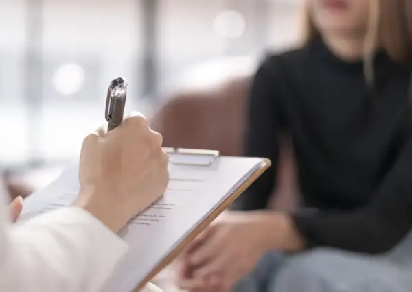 Psycholog prowadzi diagnozę różnicową, notując spostrzeżenia podczas rozmowy z pacjentem.