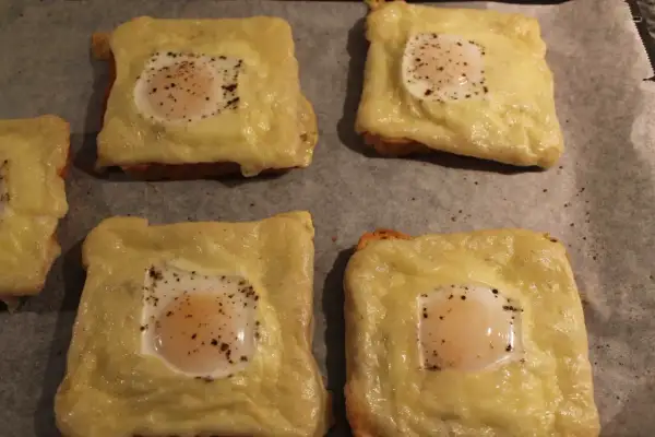 Fyra varma mackor i ugn med smält ost och ett ägg på varje. Perfekt för en snabb och god måltid.