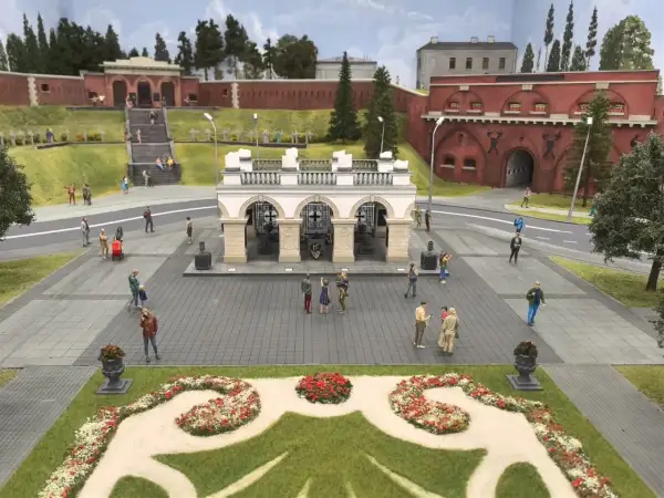 Miniaturowy park w Warszawie z ludzikami spacerującymi po placu przed bramą fortu.