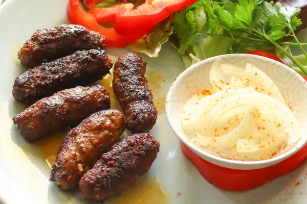 Saftige Cevapcici, perfekt gegrillt, serviert mit Zwiebeln und Salat. Ein tolles Cevapcici Rezept für jeden Anlass.