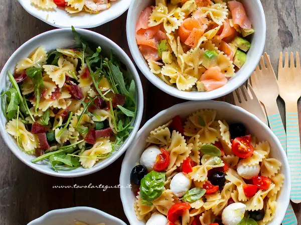 Tre idee per cosa mettere nella pasta fredda: farfalle con rucola e prosciutto, salmone e avocado, o pomodorini, mozzarelline e olive.