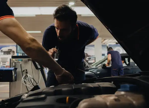 Mecánicos revisan un coche en un taller, asegurándose de que todo esté perfecto cuando se pasa la primera ITV.