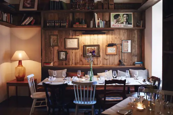 Gemütliche Atmosphäre in einem der besonderen Restaurants Berlins. Holzwände, Bücherregale und ein gedeckter Tisch laden zum Verweilen ein.