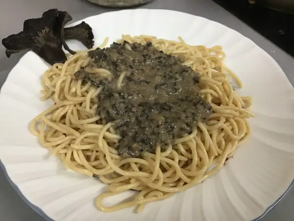 Deliciosa pasta con una cremosa salsa de trompetas de la muerte y un hongo entero como decoración.