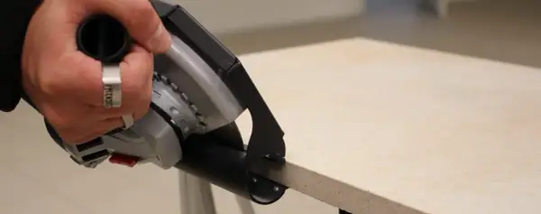 Hand mit Werkzeug schneidet Terrassenplatten. Präzises Arbeiten für die perfekte Verlegung.