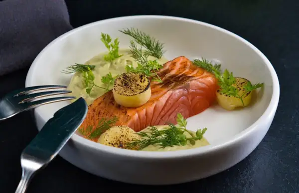 Un délicieux saumon à la toscane, servi avec une sauce crémeuse, des pommes de terre grillées et des herbes fraîches.