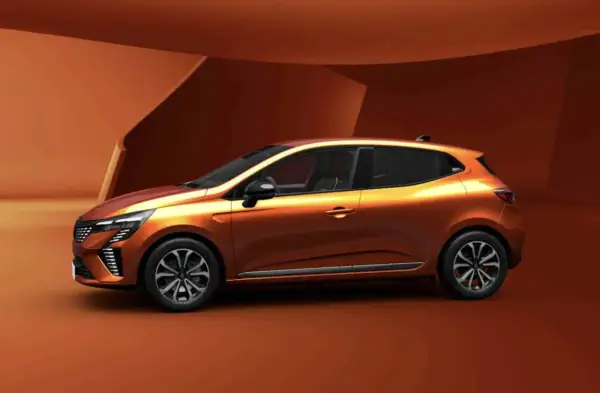 Pomarańczowy Renault Clio 6 z nowoczesnym designem, prezentowany na tle architektonicznych form w odcieniach brązu.