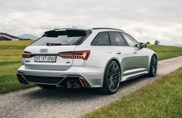 Białe Audi RS6 C8 z pakietem ABT na tle zielonych wzgórz. Widok z tyłu na sportowe detale i felgi.