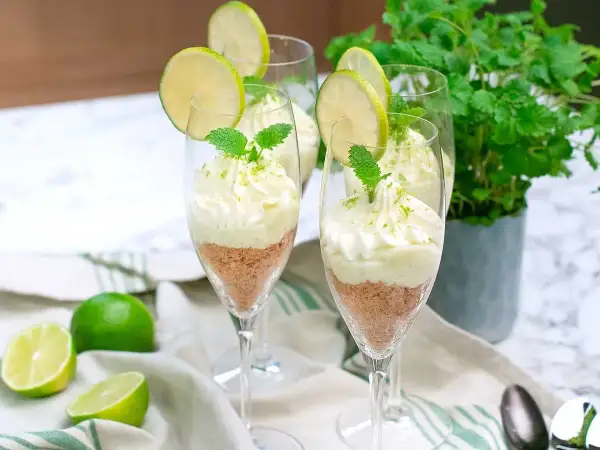 Söta key lime pie i glas, toppad med vispgrädde och lime. En perfekt dessert för sommaren.