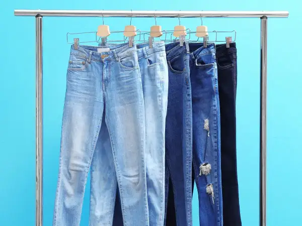 Różne modele jeansów damskich na wieszakach. Czy rozmiar 26 spodnie damskie to odpowiedni wybór?