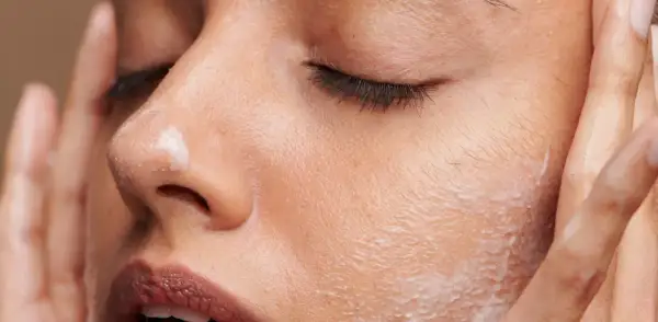 Une femme applique une crème sur son visage. C'est le moment idéal pour savoir quand appliquer crème solaire visage pour une protection optimale.