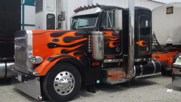Camion tuning noir et orange avec des flammes, prêt pour la nuit.