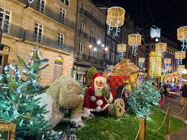 Papá Noel y un reno cubierto de nieve junto a árboles de Navidad adornados con luces. Las calles de Vigo brillan con la magia de la Navidad.