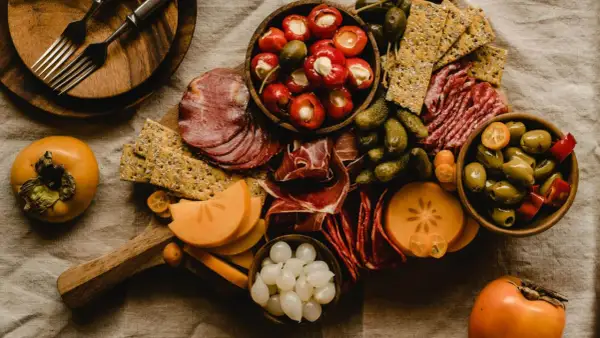 Deska serów i wędlin z owocami kaki, oliwkami i piklami. Idealna na wino aperitif.