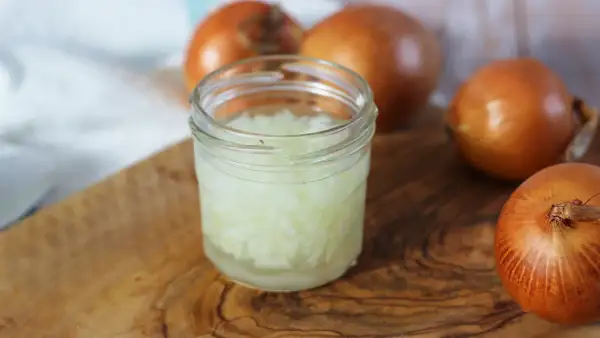 Zwiebelsaft husten: Gehackte Zwiebeln in einem Glas, bereit zur Zubereitung eines natürlichen Heilmittels gegen Husten.