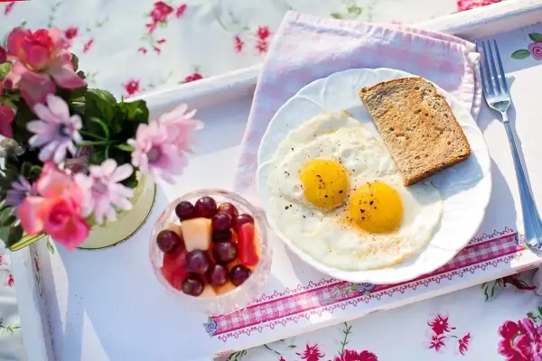 Idealne śniadanie walentynkowe: jajka sadzone, tost i owocowa sałatka. Romantyczny początek dnia.