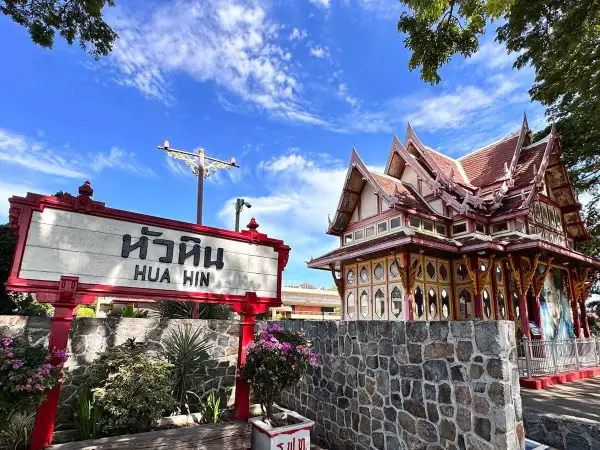 Znak "Hua Hin" przed zabytkowym budynkiem dworca kolejowego w Tajlandii.
