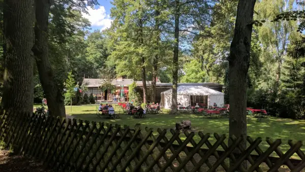 Ein Biergarten im Grünen, mit Gästen an Tischen unter Bäumen und einem Festzelt. Hier findet man **hanffs ruh**.
