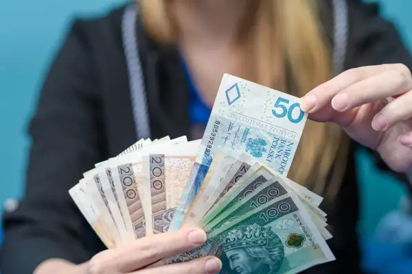 Dłoń trzyma plik polskich banknotów: 50, 100 i 200 zł. Może to być oferta kredytu w Revolut.