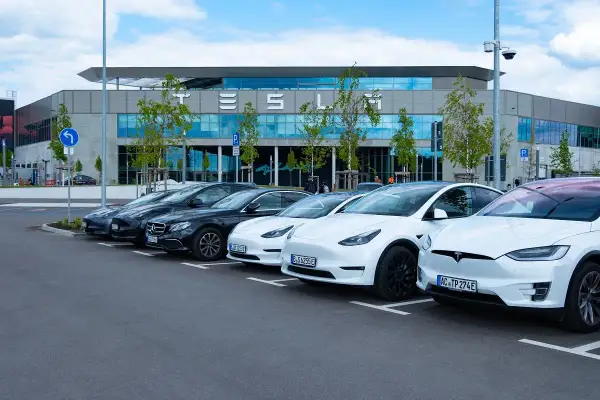 Rząd białych i czarnych Tesli zaparkowany przed budynkiem z napisem "TESLA". Czy to Tesla z jakiego kraju?
