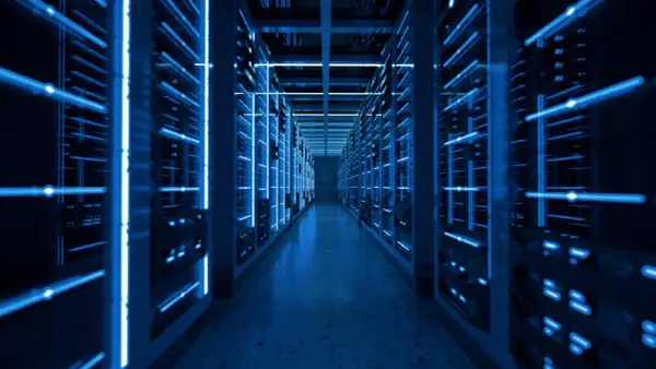 Wnętrze nowoczesnego data center z rzędami serwerów oświetlonych niebieskim światłem.