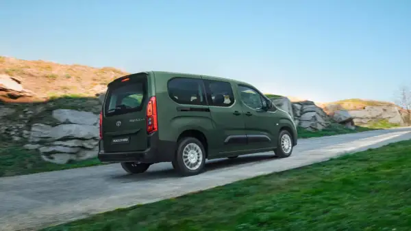 Zielony, używany Toyota Proace City Verso jedzie po krętej drodze wśród skał i zieleni.