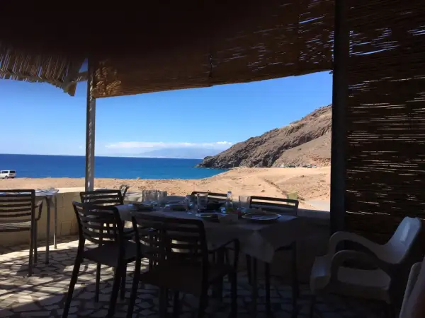 Mesas puestas en restaurantes en La Fabriquilla, Cabo de Gata, con vistas al mar y a la montaña.