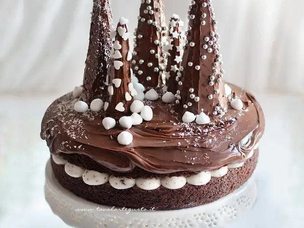 Una magica torta di Natale al cioccolato, decorata con alberelli innevati e dolci fiocchi di neve.