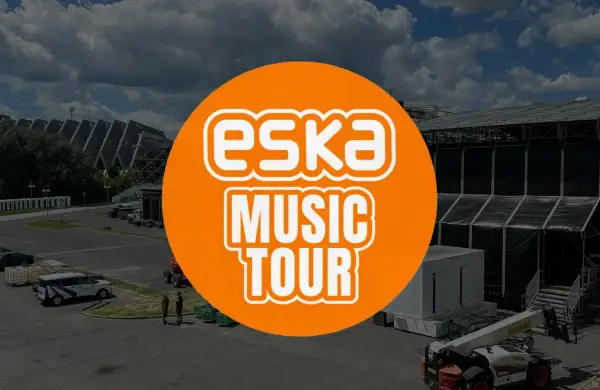 Pomarańczowe koło z napisem "ESKA MUSIC TOUR" na tle sceny koncertowej i parkingu.