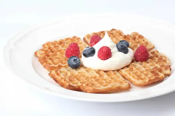 Små, gyllene våfflor med fluffig grädde och färska bär. Ett perfekt resultat av ett enkelt våffelsmet recept.