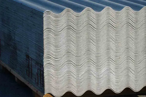 Lastra ondulata in fibrocemento ecologico, impilata su pallet. Materiale da costruzione resistente e durevole.